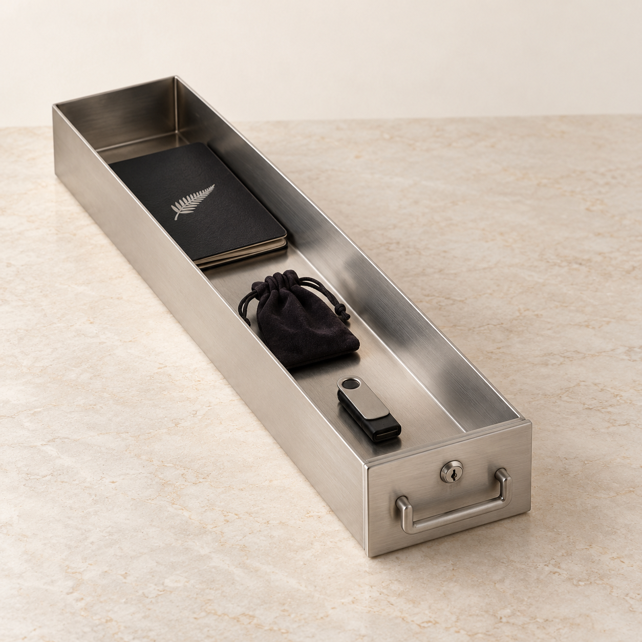 Representative image of a long, narrow brushed-steel Mini box holding a passport, a small drawstring jewellery pouch and a USB drive