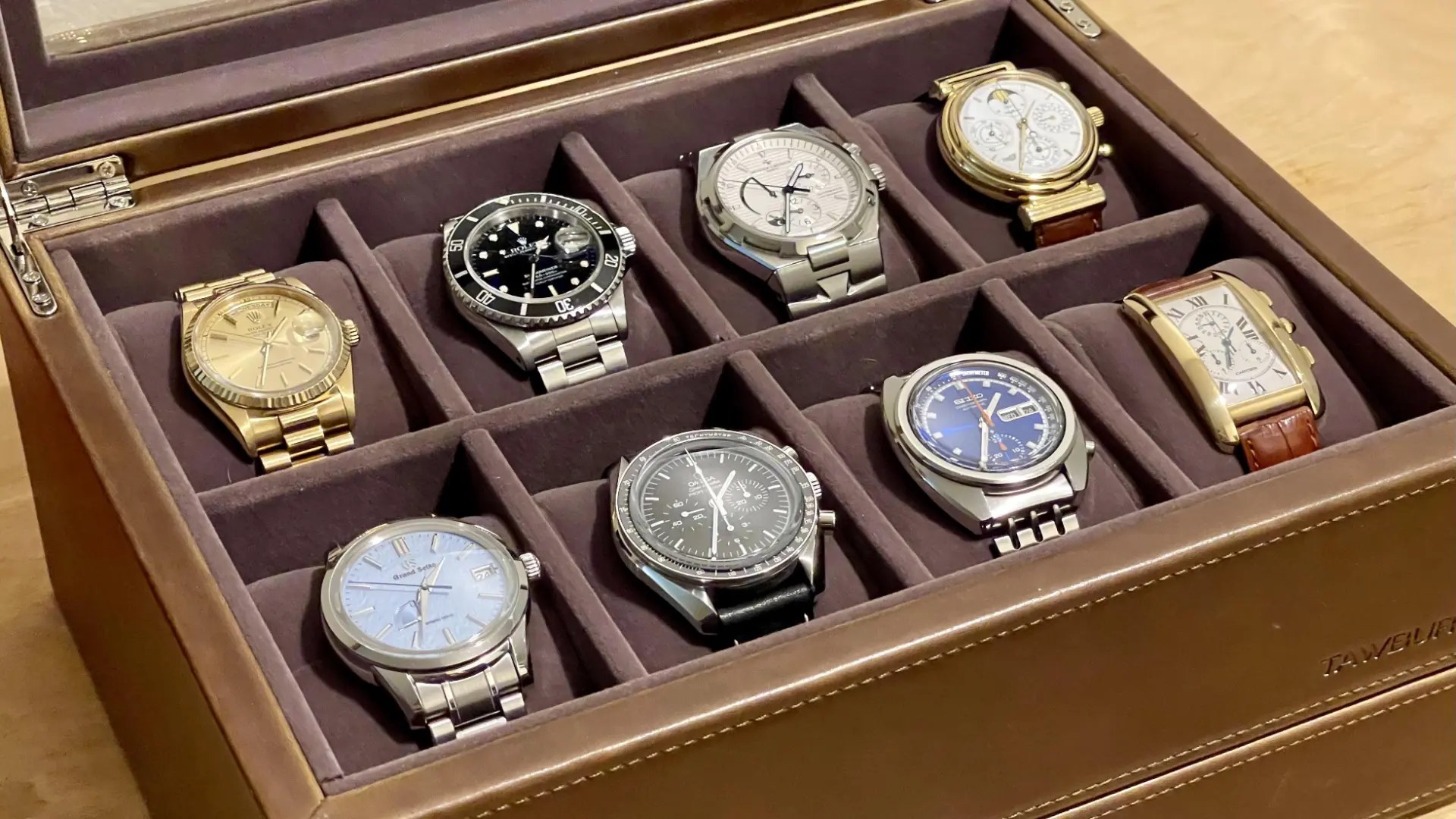 A collection of wristwatches arranged in a leather storage case.